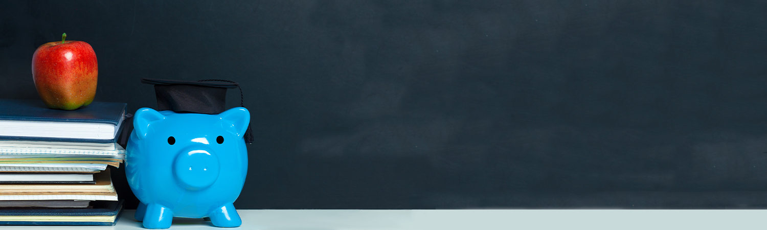 Apple on a Stack of Books Next to Blue Piggy Bank Wearing a Grad Cap in Front of a Chalk Board