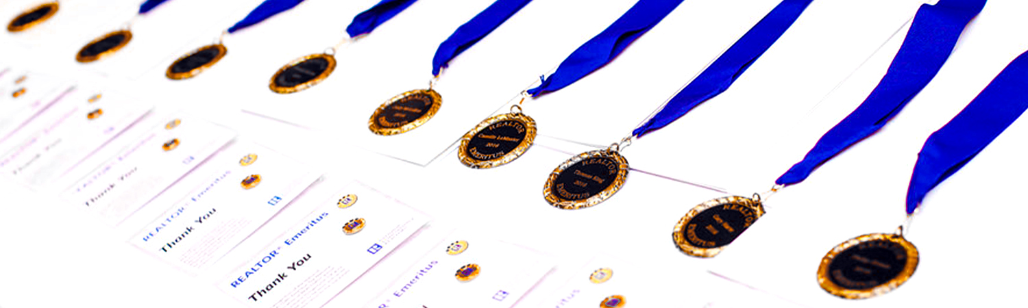 Row of REALTOR&reg; Emeritus Medals and Badges Lined on a Table